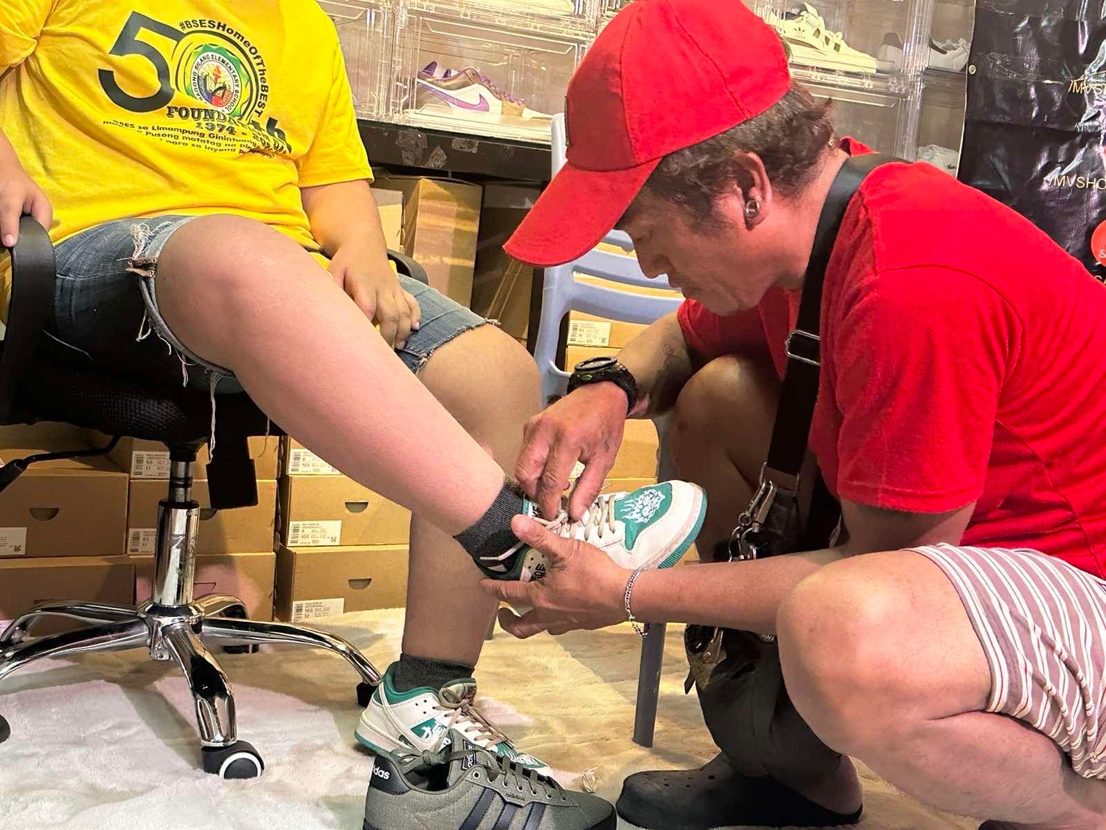 Ramil Albano, who tattooed his forehead the name of a Takoyaki resto, puts shoes on his son, who has Down syndrome. Andrea Taguines, ABS-CBN News